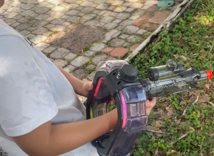 Kid gripping the Neon Electric Water Blaster with the LED loop lit pink